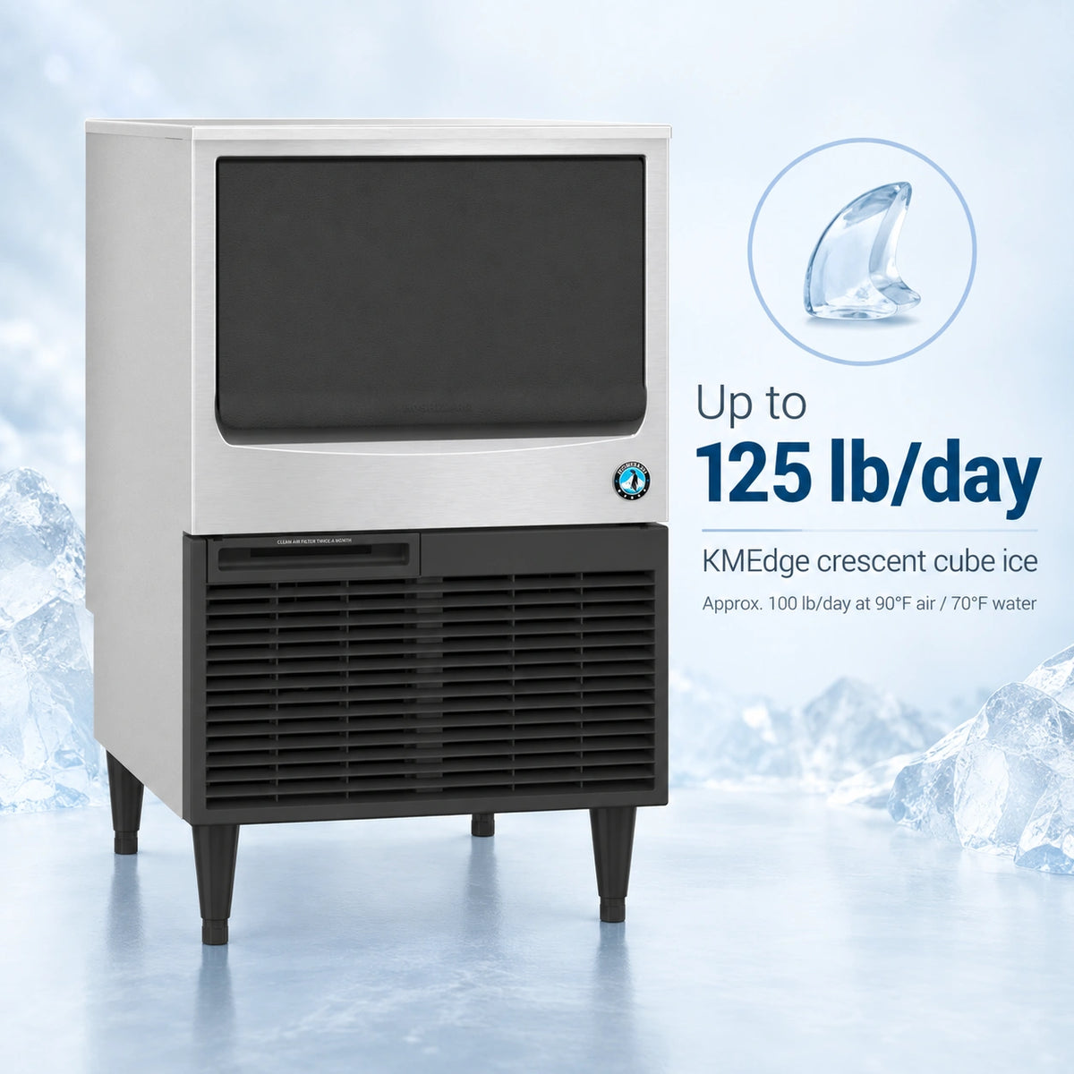 A KMEdge commercial ice machine with a white upper cabinet and black lower grille, shown on a icy blue background with promotional text reading 'Up to 125 lb/day' and a small ice crystal graphic.
