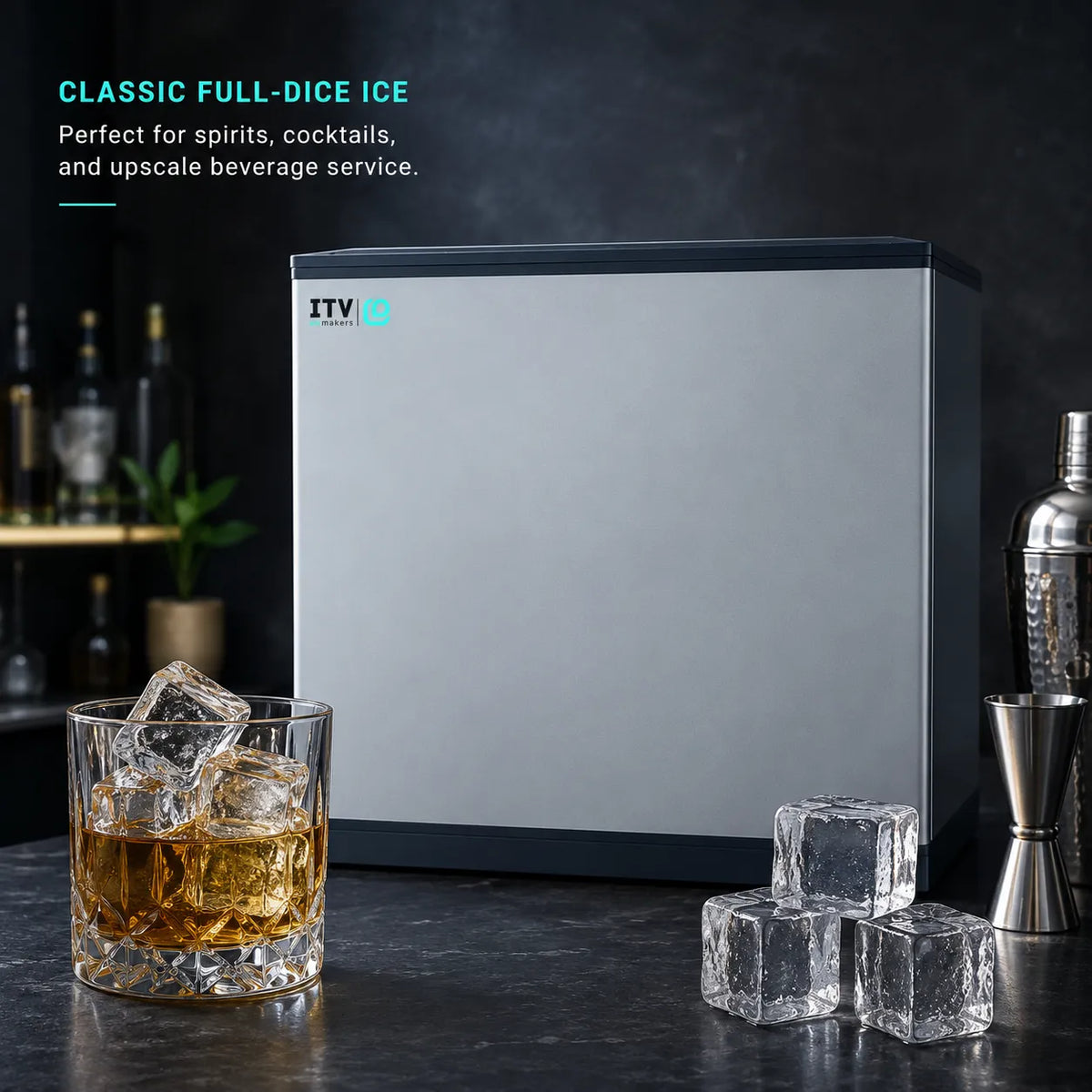 A silver and black countertop ice dispenser shown on a dark bar counter with an ice cube tray, a glass of amber liquor, and cocktail accessories. Text on the left reads 'CLASSIC FULL-DICE ICE' and 'Perfect for spirits, cocktails, and upscale beverage service.
